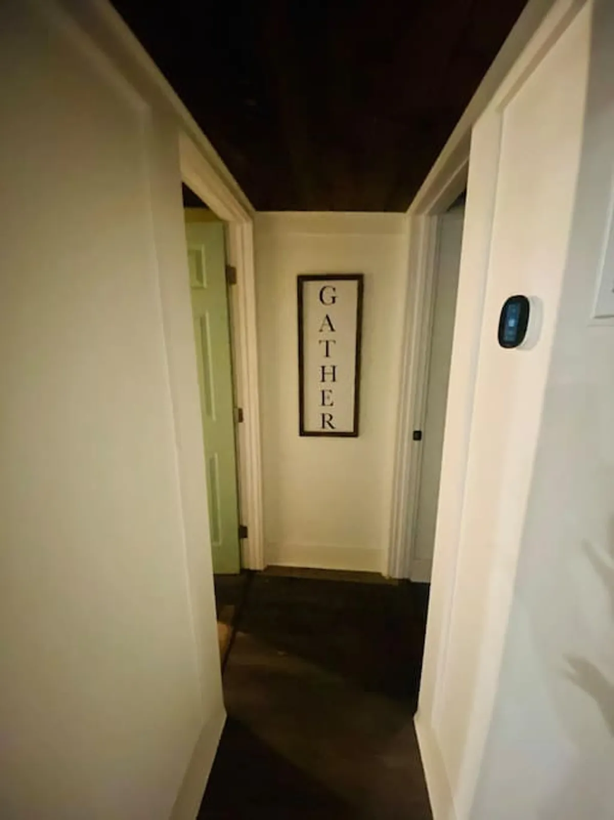 A welcoming green door and a prominent 'GATHER' sign create an inviting entryway atmosphere, hinting at the threshold between indoor comfort and outdoor exploration. The mood is welcoming, emphasizing togetherness before or after a day of adventure.